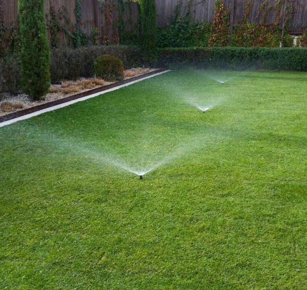 Aspersores de riego regando un césped verde en un jardín