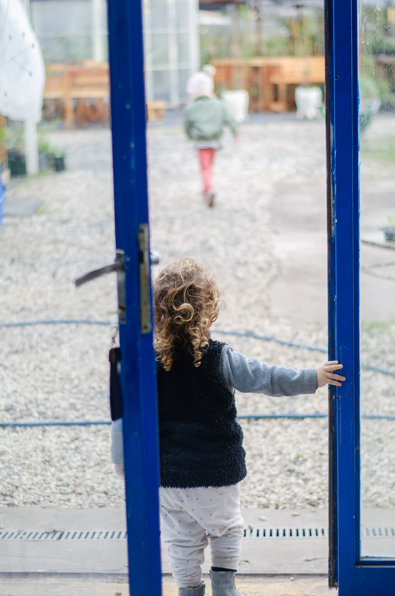 Niña abriendo la puerta azul del vivero
